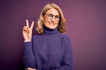 Middle age beautiful blonde woman wearing casual purple turtleneck sweater and glasses smiling with...