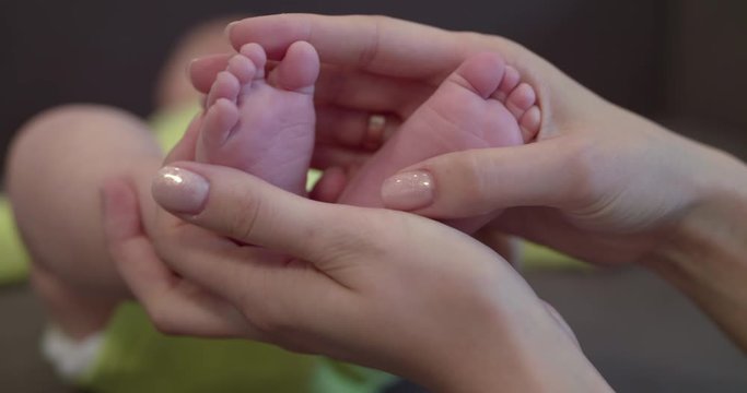 Mom's hands holds baby's cute feet at camera