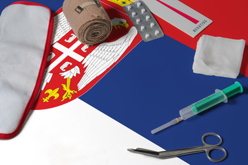 Serbia flag with first aid medical kit on wooden table background. National healthcare system concept, medical theme.