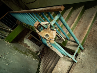 Gas mask hanging on the staircase handrail. Chernobyl Exclusion Zone. Ukraine