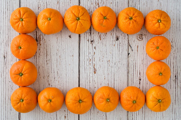 Small clementine oranges in a rectangular shape on a whitewashed wood background
