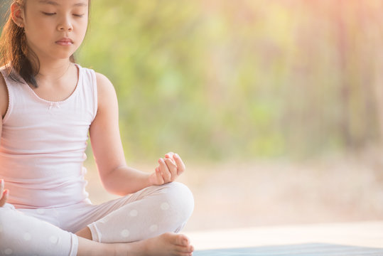 calmness and relax, female happiness.Horizontal, blurred background. little asian girl meditates while practicing yoga. freedom concept. calmness and relax, child happiness. toned picture healthy life
