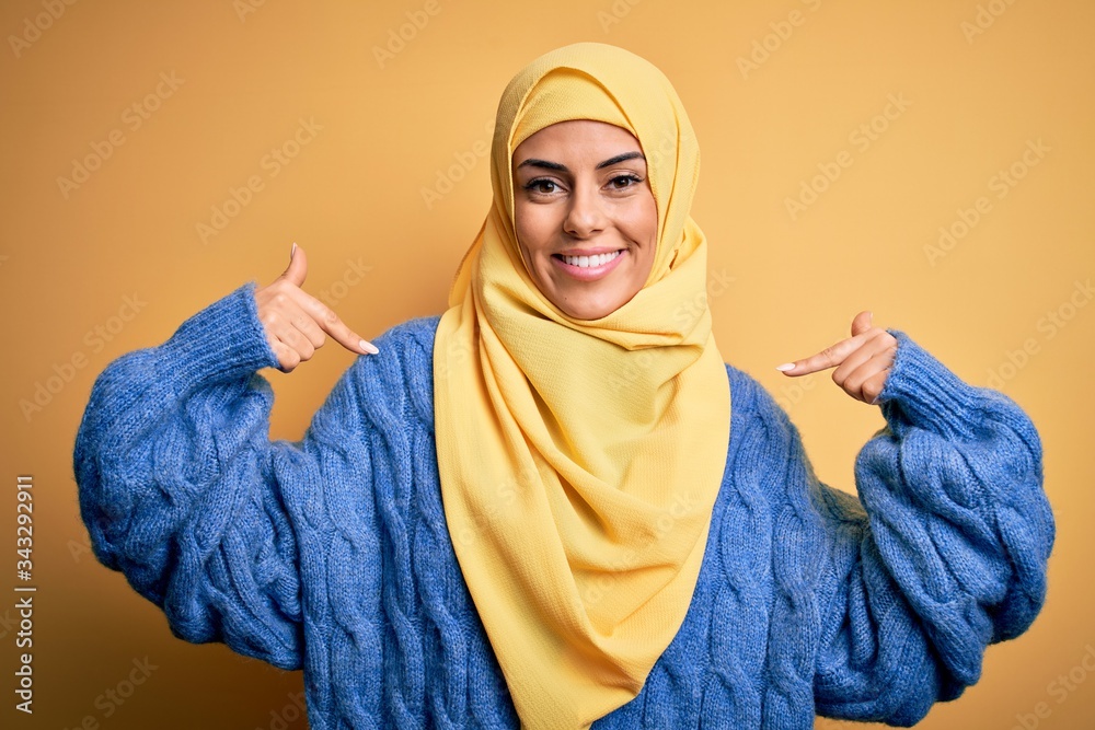 Sticker young beautiful brunette muslim woman wearing arab hijab over isolated yellow background looking con