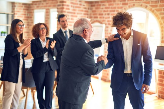 Group of business workers smiling happy and confident. Two of them, standing with smile on face shaking hands for agreement. Partners applauding at the office.