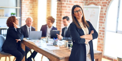 Group of business workers smiling happy and confident working together in a meeting. One of them, standing with smile on face looking at camera at the office.