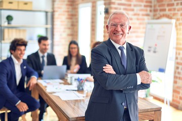 Group of business workers smiling happy and confident working together in a meeting. One of them, standing with smile on face looking at camera at the office.