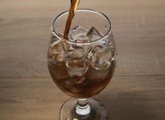 carbonated drink is poured into a glass with ice