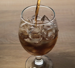 carbonated drink is poured into a glass with ice