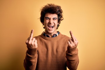 Young handsome man wearing casual shirt and sweater over isolated yellow background Showing middle...