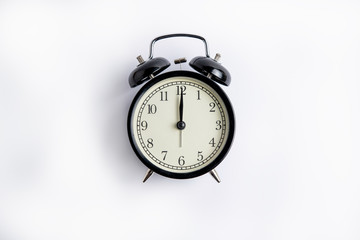 black alarm clock on a white background, on the dial 12 o'clock, alarm clock on 6