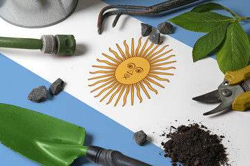 Argentina flag with gardening tools background on table. Spring in the garden concept with free...