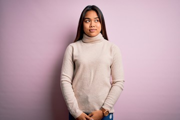 Young beautiful asian girl wearing casual turtleneck sweater over isolated pink background smiling looking to the side and staring away thinking.