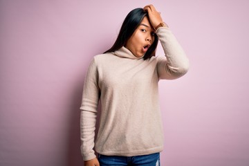 Young beautiful asian girl wearing casual turtleneck sweater over isolated pink background...