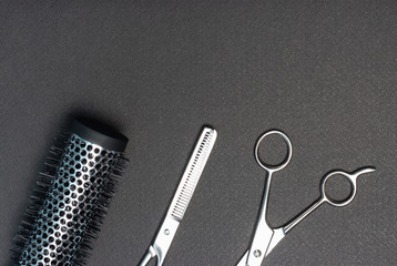 Hairdressing scissors, a comb, on a black background, the copy space