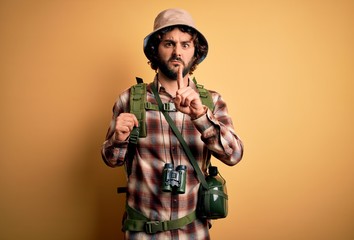 Young hiker man with curly hair and beard hiking wearing backpack and water canteen Pointing with finger up and angry expression, showing no gesture