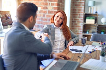 Young beautiful couple of business workers smiling happy and confident. Shaking hands with smile on face for agreement at office
