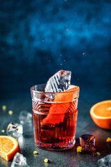 Fresh grapefruit cocktail with mint and ice in jar glass on dark blue background. Studio shot of drink in freeze motion, flying ice, drops in liquid splash. Summer cold drink and cocktail