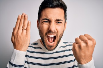 Handsome man with beard showing alliance ring marriage on finger over white background annoyed and frustrated shouting with anger, crazy and yelling with raised hand, anger concept