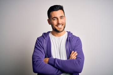 Young handsome man wearing purple sweatshirt standing over isolated white background happy face smiling with crossed arms looking at the camera. Positive person.