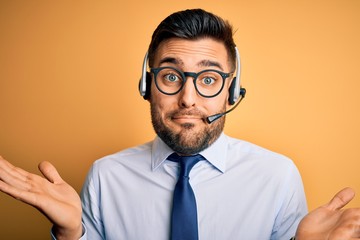 Young business operator man wearing customer service headset from call center clueless and confused...