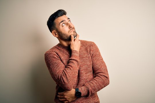 Young handsome man wearing casual sweater standing over isolated white background Thinking worried about a question, concerned and nervous with hand on chin