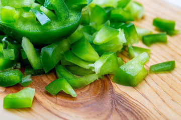 A juicy bell pepper. Sweet green pepper sliced small pieces on a wet wooden board. Health vegetarian food. Macro.