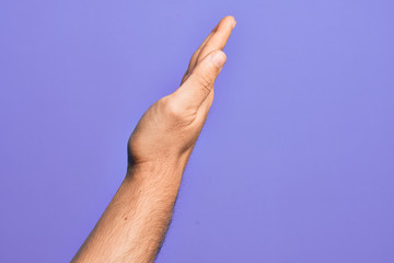 Hand of caucasian young man showing fingers over isolated purple background showing the side of stretched hand, pushing and doing stop gesture