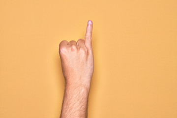 Hand of caucasian young man showing fingers over isolated yellow background showing little finger...