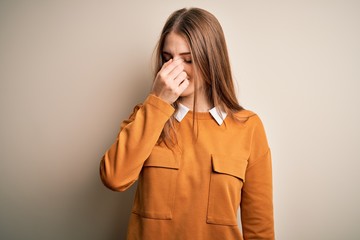 Young beautiful redhead woman wearing casual sweater over isolated white background tired rubbing nose and eyes feeling fatigue and headache. Stress and frustration concept.
