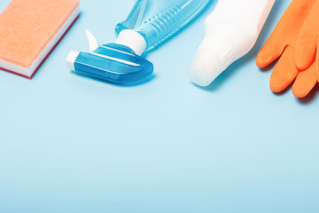 Bottle with spray, gloves and rag on blue background, a copy of the space
