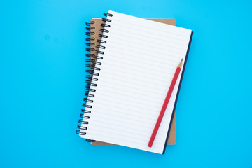 Top view above of open blank spiral notebook and red pencil isolated on light blue background for design a mockup. Education and business concept. flat lay