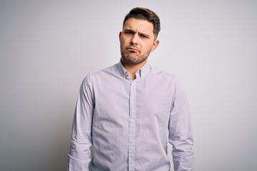 Fototapeta premium Young business man with blue eyes standing over isolated background skeptic and nervous, frowning upset because of problem. Negative person.