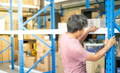 Back view of male hand preparing to assembling the metal rack  in warehouse or storage and shelves for cardboard boxes of products.