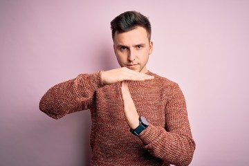 Young handsome caucasian man wearing casual winter sweater over pink isolated background Doing time...
