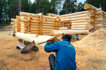 Build a house from logs. Preparation of logs for the assembly of the structure. Assembly of a...