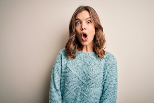 Young blonde girl wearing casual blue winter sweater over isolated background afraid and shocked with surprise expression, fear and excited face.
