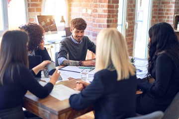 Group of business workers smiling happy and confident. Working together with smile on face  using laptop and speaking at the office