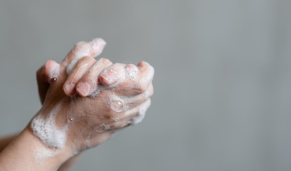 Closeup of person washing hands on gray background. Empty space for text