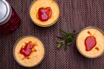 Three creme brulee desserts on a brown tablecloth next to a berry drink