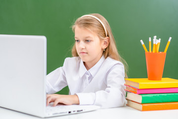 Smart young girl uses laptop in a school