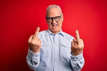 Middle age handsome hoary man wearing casual striped shirt and glasses over red background Showing...