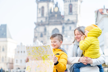 Happy family holds map on the old town square in Prague. Empty space for text