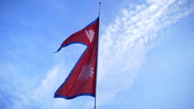 Nepali flag waving in wind with a blue sky in the background. Real, non-animated, Double Triangular. Only non-rectangular most unique flag in the world.