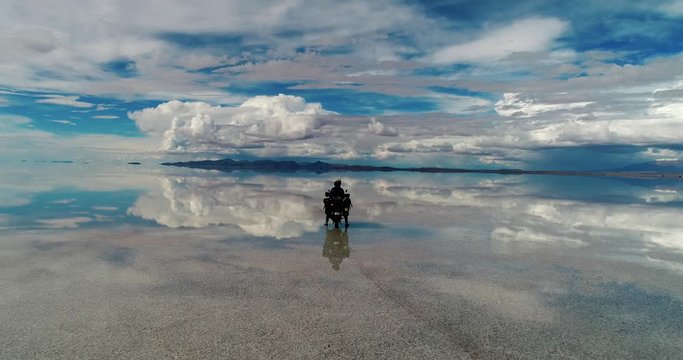 Salt flat in Bolivia Uyuni South America during wet season. Motorcycle rider Mirror reflection off the water. Filmed on DJI Drone Phantom Pro