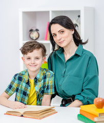 Portrait of a young woman and her son doing homework together at home