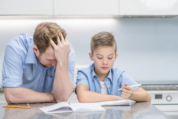 Sad man and his son doing homework together at home