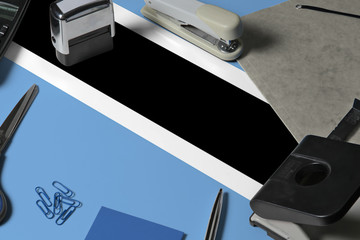 Botswana flag with office clerk workplace background. National stationary concept with office tools.