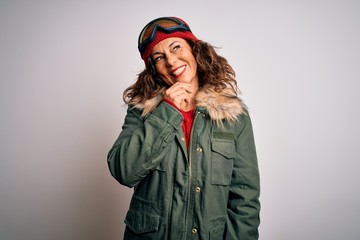 Middle age skier woman wearing snow sportswear and ski goggles over white background looking confident at the camera with smile with crossed arms and hand raised on chin. Thinking positive.