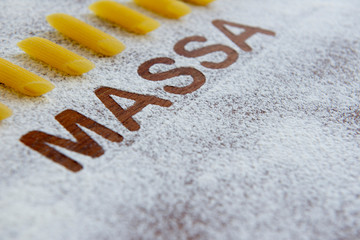 wooden background with sprinkled flour and the word pasta written