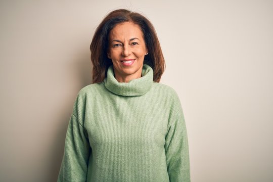 Middle age beautiful woman wearing casual turtleneck sweater over isolated white background with a happy and cool smile on face. Lucky person.